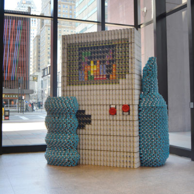 Canstruction build created with canned goods depicting hand holding a Nintendo Gameboy playing Tetris